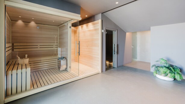 Una sauna moderna con listones de madera, un banco y una pequeña cesta.