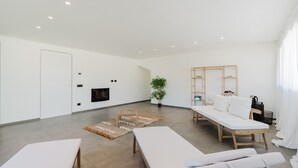 Una habitación amplia con una cama grande, una mesita, un banco y un televisor montado en la pared.