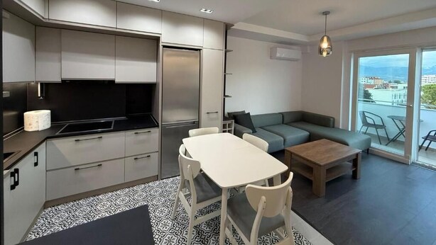 Un appartement moderne comprenant un coin cuisine, un espace repas et un salon avec un canapé et une table.