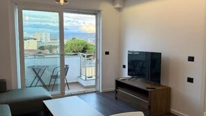 Un salon moderne doté d’une grande fenêtre, d’un téléviseur à écran plat, d’une table à manger et d’un canapé.
