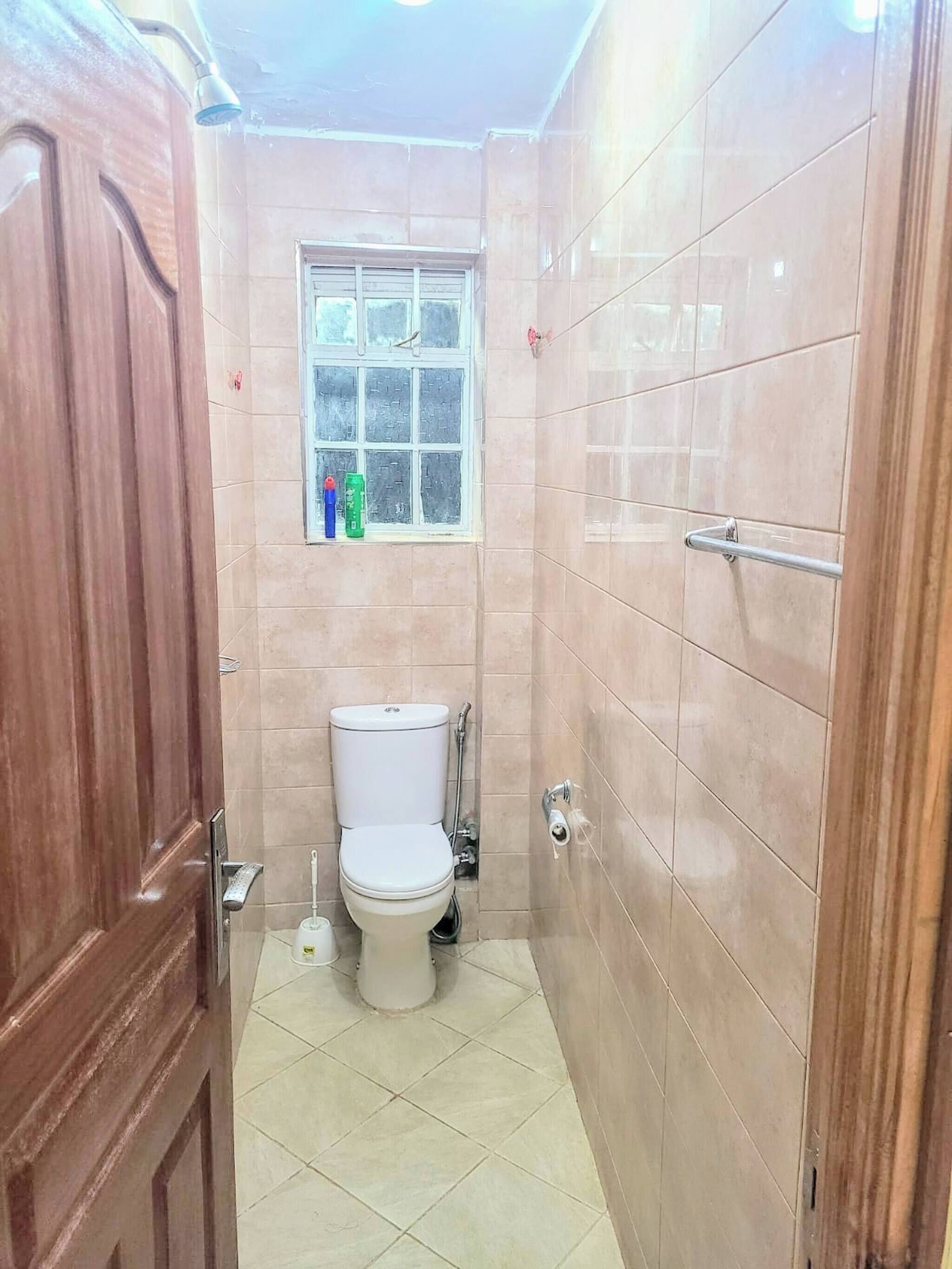 Un baño pequeño con inodoro, ventana y zona de ducha.