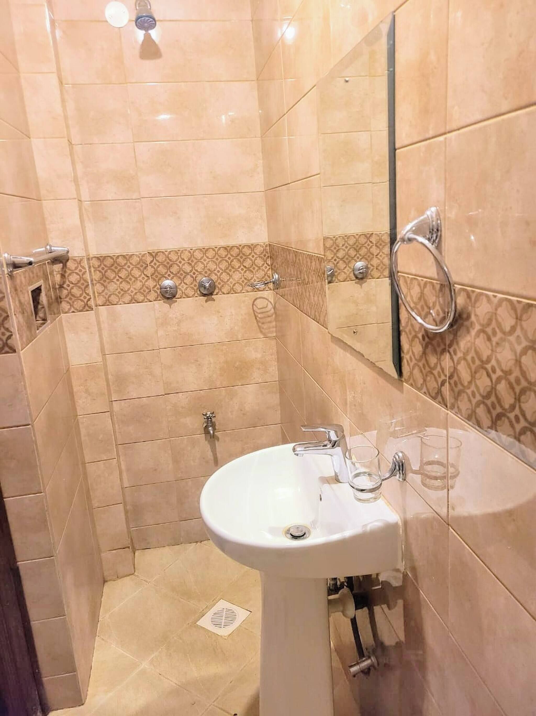 Een badkamer met beige tegels, een wit wastafelmeubel en een spiegel.