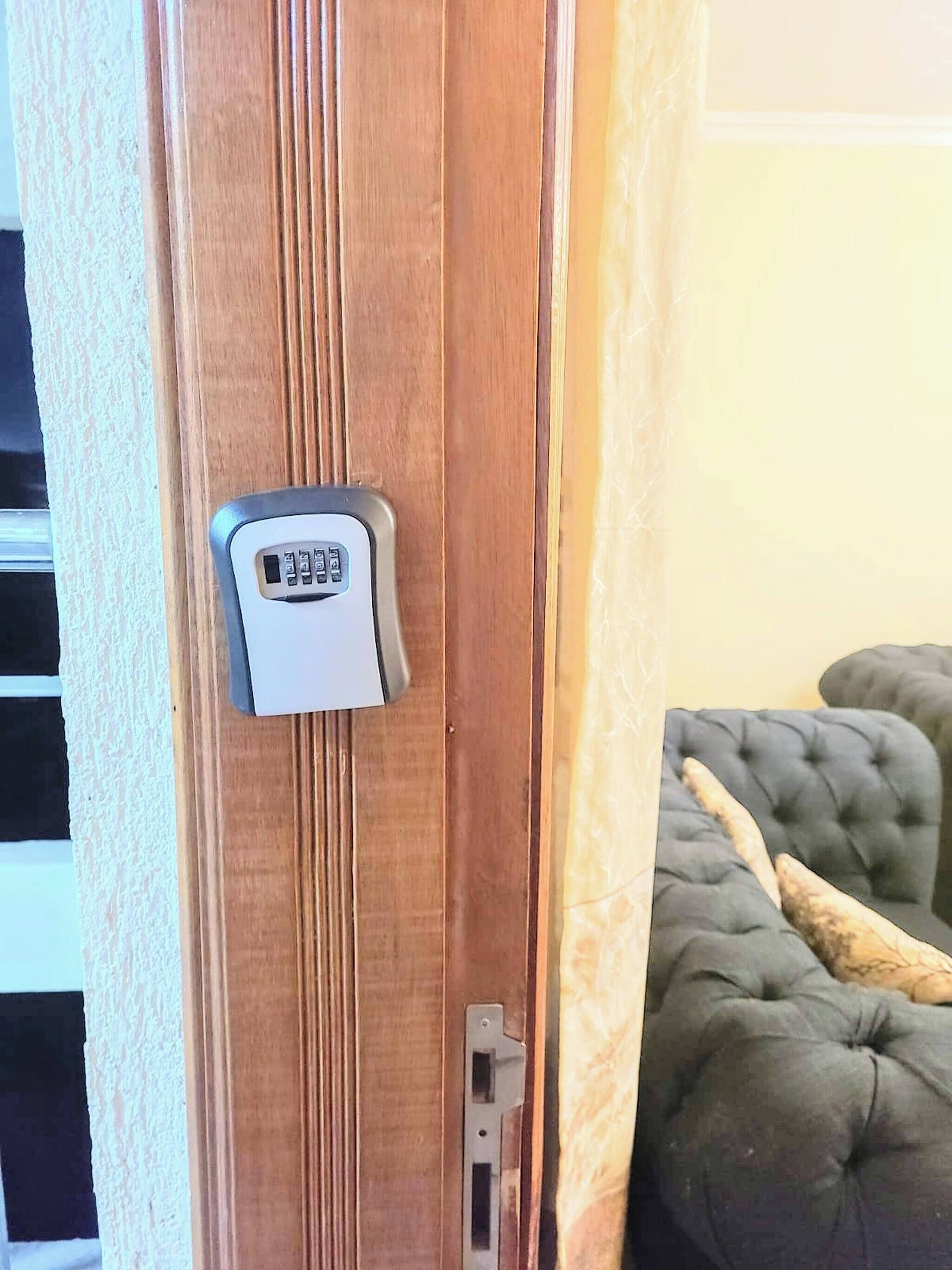 Una puerta con teclado electrónico, panel de madera y sillón mullido.