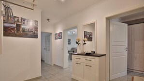 A hallway with a white cabinet, a mirror, and artwork on the walls. - Ostsee Domizil, App. 1 (Timmendorfer Strand)