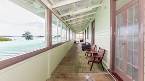 A covered porch with a view of the water, wooden benches, and a table. - The Happy Pelican Harrington Hotel (Harrington)