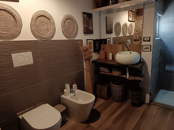 Une salle de bain moderne avec un plancher en bois, des toilettes blanches, un bidet et un meuble-lavabo doté d’un grand lavabo blanc.