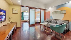A modern hotel room with a wooden desk, a sofa, and a green armchair. There is a TV on the wall and a bed in the background. - Pazhou Poya International Hotel Canton Fair Complex Modiesha Metro Exit B Branch - Free Shuttle Bus to Canton Fair Complex During Canton Fair Period (Guangzhou)