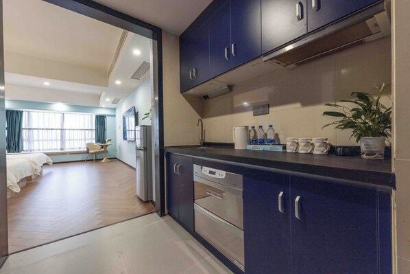 A modern kitchen with dark blue cabinets, a dishwasher, and a countertop with kitchen essentials. - Pazhou Poya International Hotel Canton Fair Complex Modiesha Metro Exit B Branch - Free Shuttle Bus to Canton Fair Complex During Canton Fair Period (Guangzhou)
