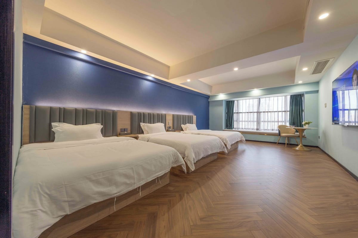 Ein Hotelzimmer mit drei Betten, einem Schreibtisch und einem Stuhl.
