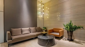A modern interior with a sofa, armchair, round coffee table, and a potted plant. - Pazhou Poya International Hotel Canton Fair Complex Modiesha Metro Exit B Branch - Free Shuttle Bus to Canton Fair Complex During Canton Fair Period (Guangzhou)