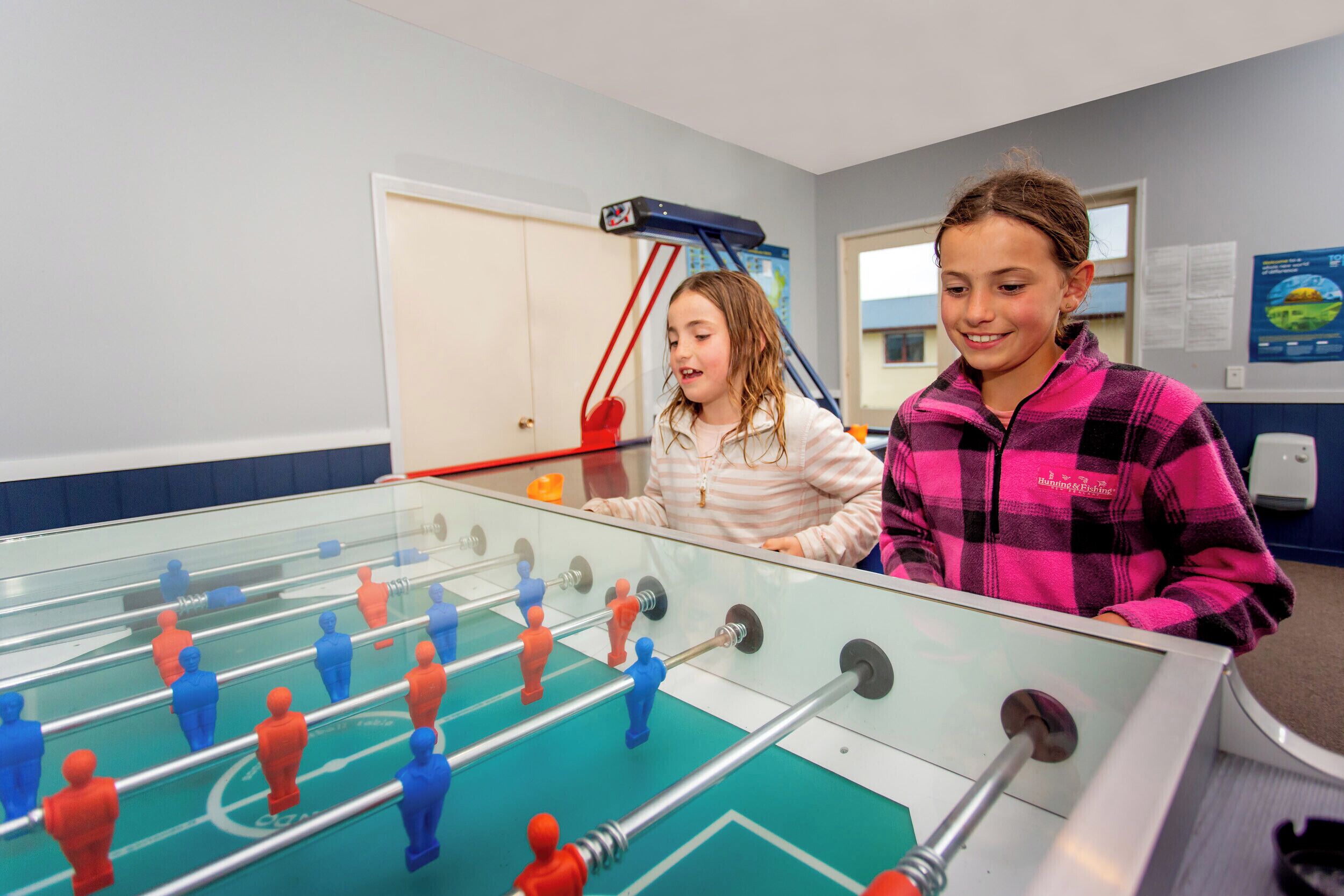 A foosball table in a room with a door and a poster on the wall.