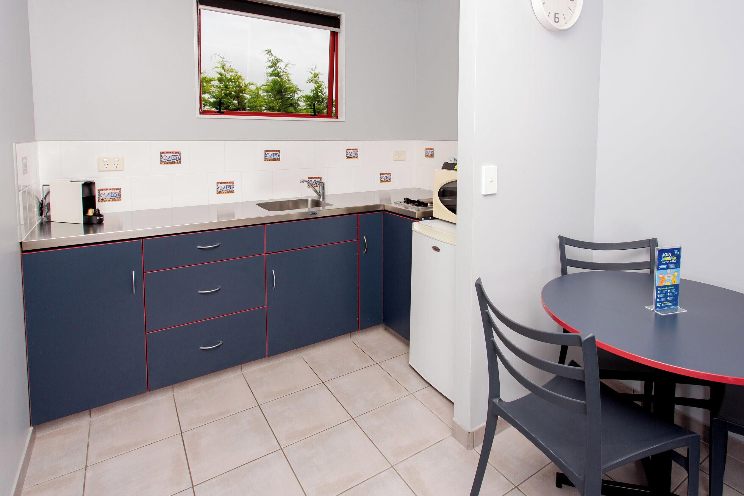 A compact kitchen with a sink, cabinets, and a dining area with chairs and a table.
