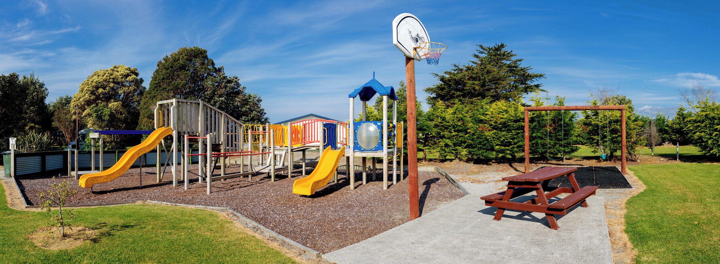 A playground with slides, climbing structures, and a basketball hoop.