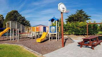 A playground with slides, climbing structures, and a basketball hoop.