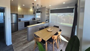 A modern kitchen with a central island, built-in appliances, and a large window offering a view. - Carters Beach Top 10 Holiday Park (Westport)