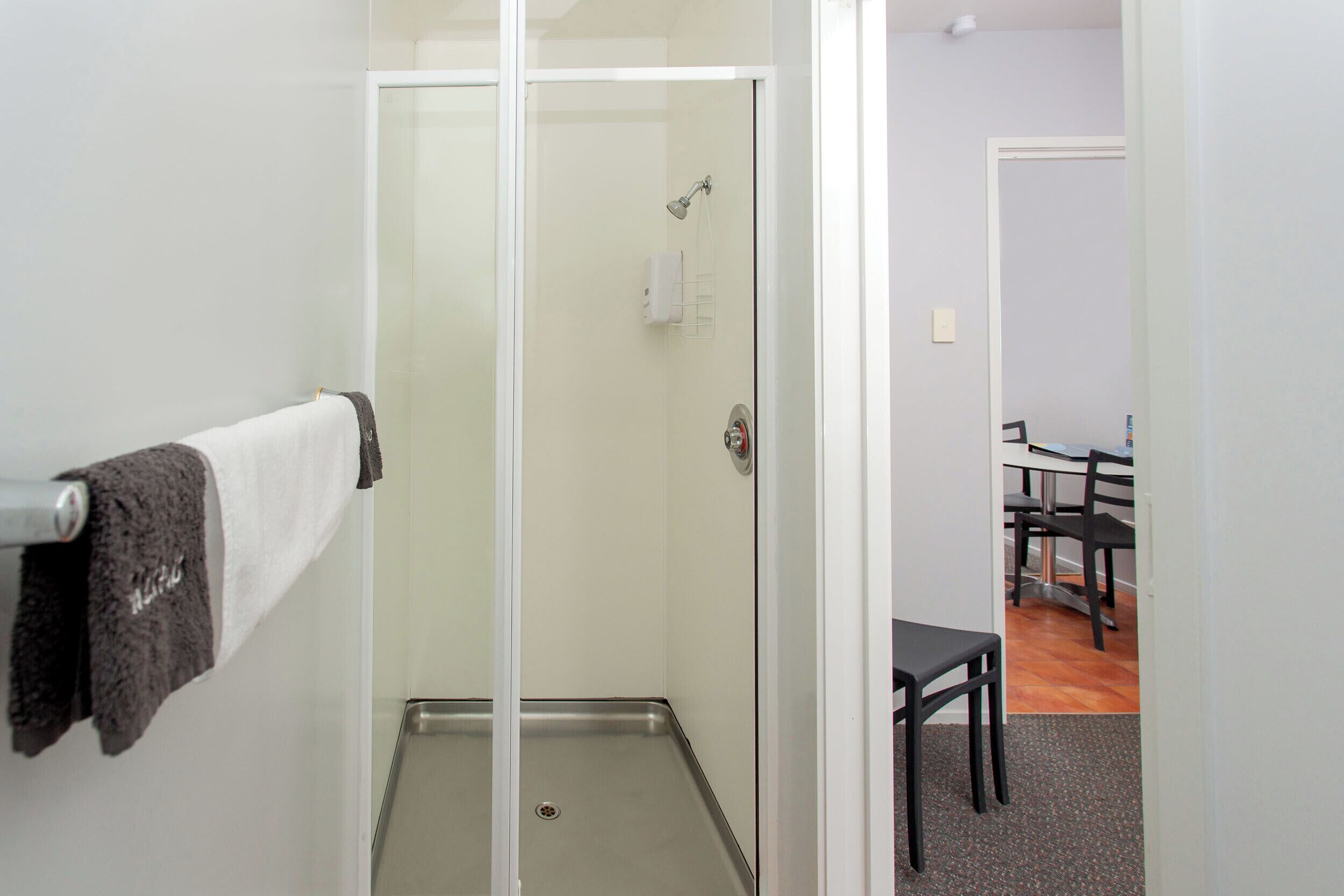 A bathroom with a glass shower enclosure, a towel rack with a towel, and a visible showerhead.
