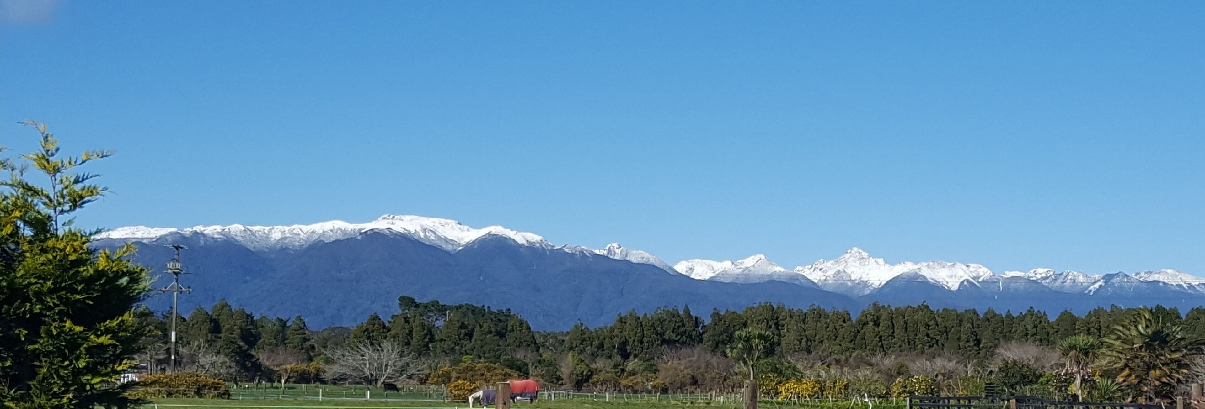 A mountain landscape with snow-capped peaks and a clear blue sky.