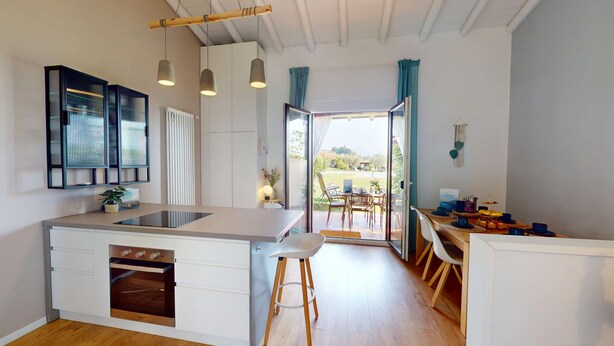A modern kitchen with a central island, built-in oven, and pendant lighting. - Harmonia Cottage by Bookinggardalake (Soiano del Lago)