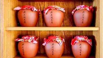 A wooden shelf with six terracotta pots, each adorned with a red and white floral cloth and black Chinese characters.