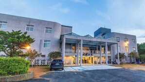 Un hotel moderno con entrada cubierta, varios pisos y zona de estacionamiento.