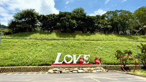 Zona ajardinada con un cartel que dice 'LOVE' y decoraciones con forma de corazón.
