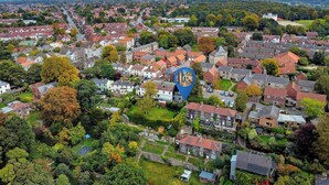 Vista aérea de una zona residencial con casas, árboles y cielo despejado.