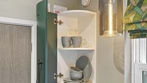 Una cocina con un mueble empotrado que contiene utensilios de cocina y un reloj en la pared.