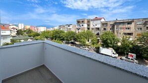 A balcony with a view of residential buildings and parked cars.