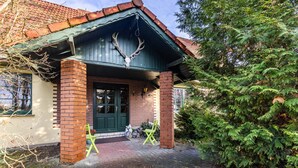 A building with a brick facade, a green door, and a deer skull mounted on the roof. - Apartment 'Für Monteure' with Wi-Fi (Templin)