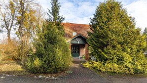 A building with a brick facade, a green door, and a small porch with a chair. - Apartment 'Für Monteure' with Wi-Fi (Templin)