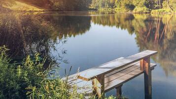 A wooden dock extending into a calm lake surrounded by dense forest.