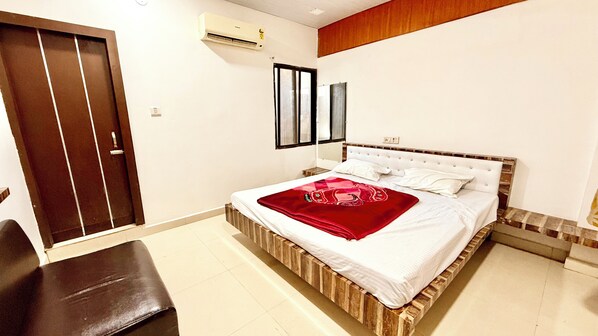 A bedroom with a bed, a bench, a wardrobe, and an air conditioning unit.