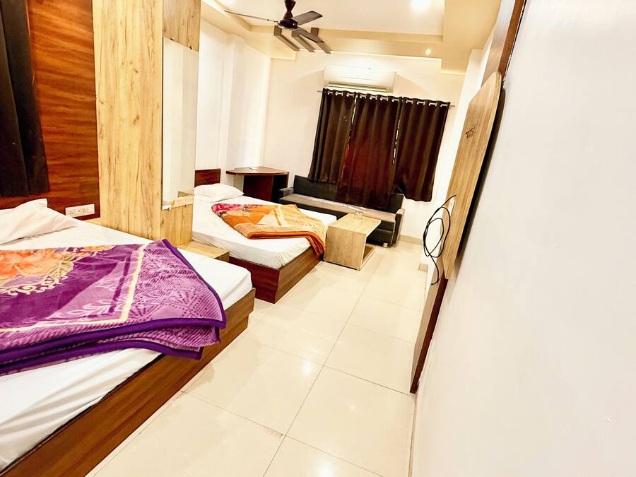 A hotel room with a bed, a sofa, a small table, a TV, and a ceiling fan.