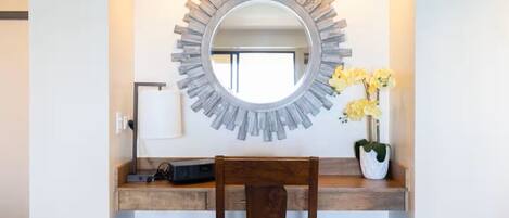 A modern vanity with a circular mirror, wooden countertop, and a chair.