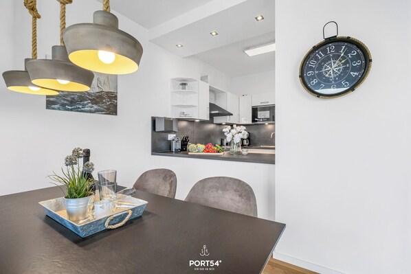 A modern dining area with a dark wooden table, a decorative tray, and a potted plant. - Portus - Sea view, balcony, barbecue, walk-in shower, fireplace (Olpenitz)