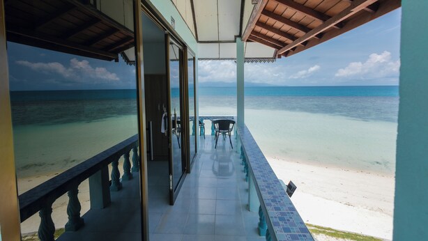 Un balcon fermé offrant une vue sur une plage et l’océan.