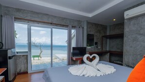 Une chambre d’hôtel avec un lit, une télévision, un bureau et vue sur la plage.