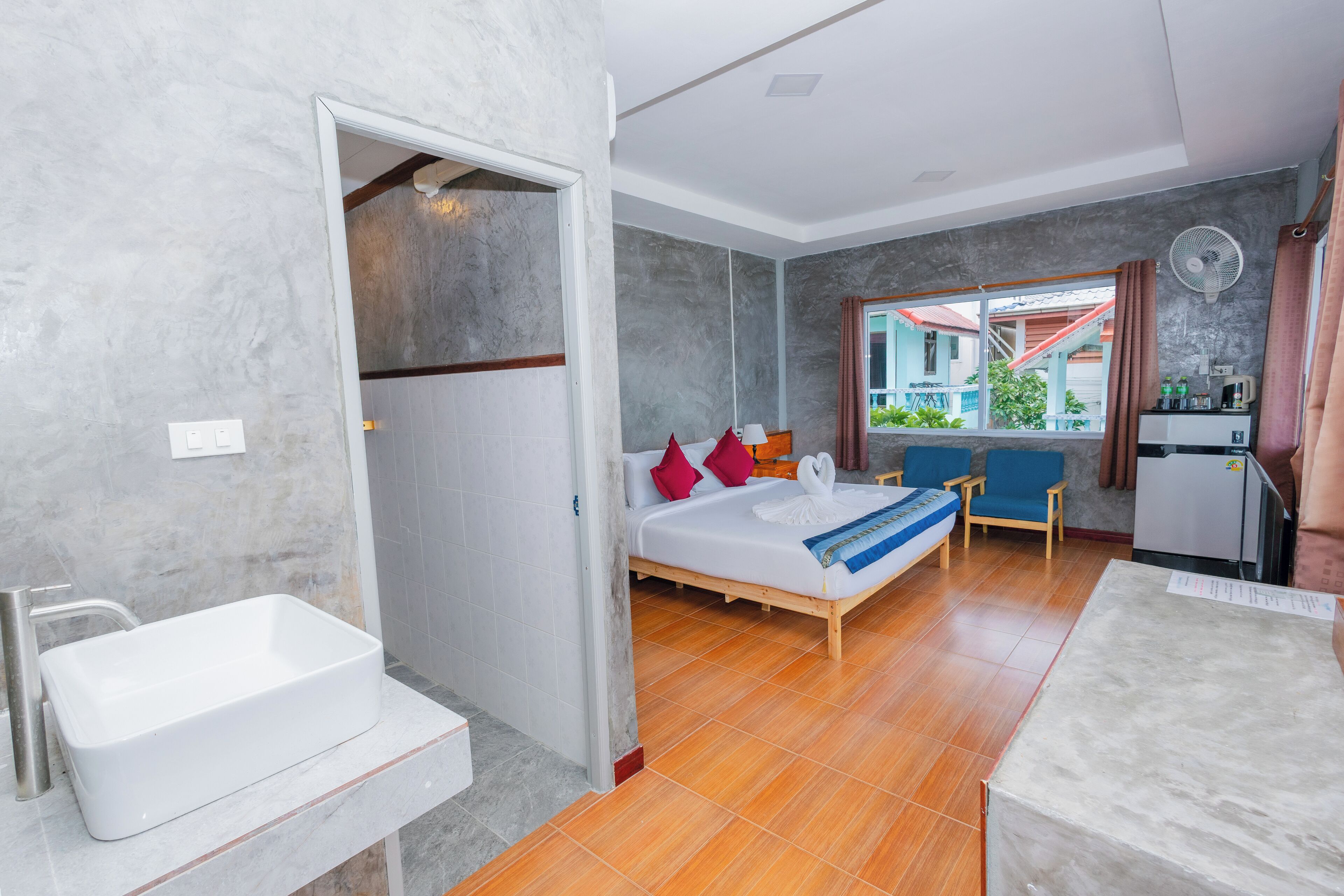 Une chambre d’hôtel avec un lit, un petit bureau, un lavabo et une fenêtre donnant sur l’extérieur.