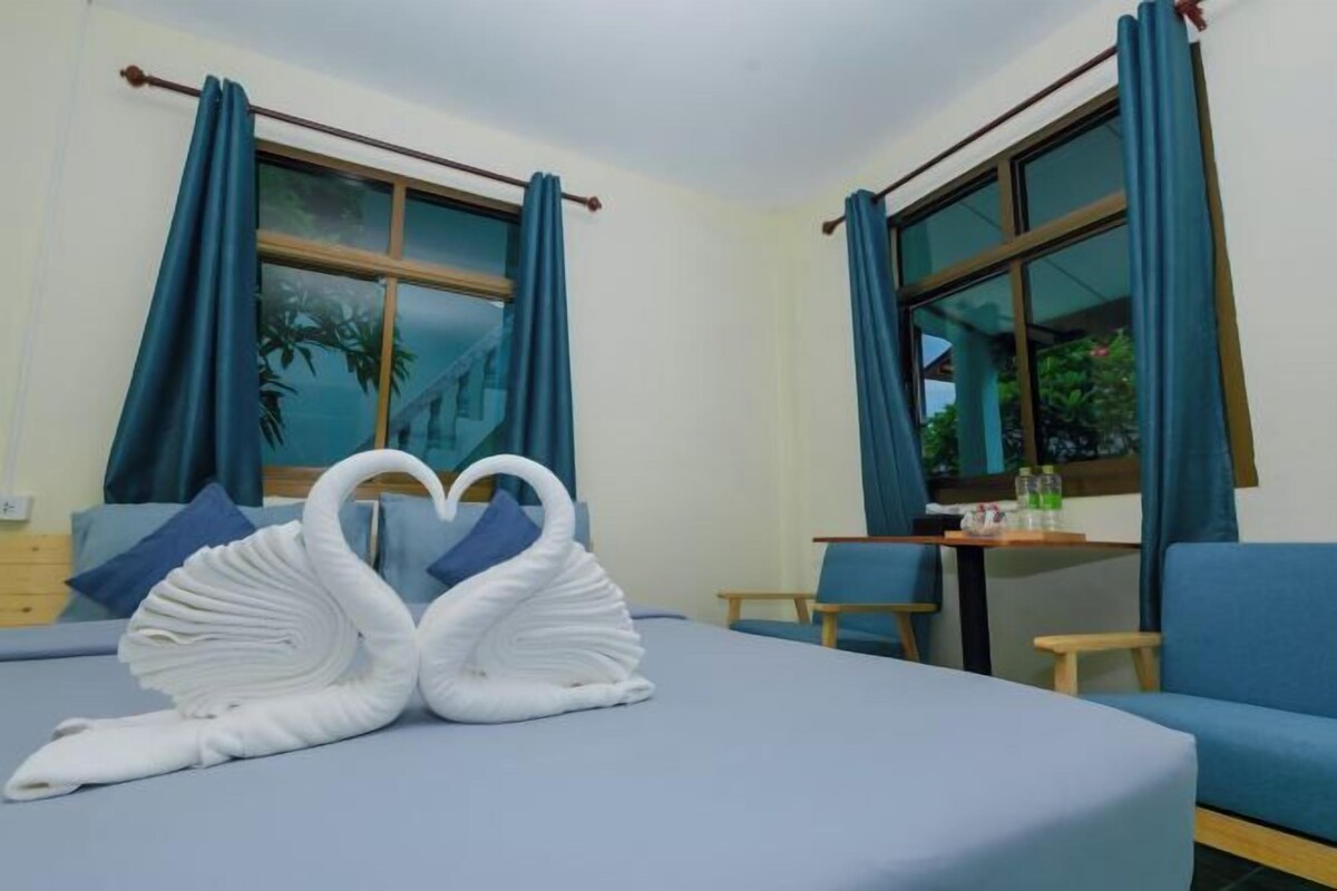 Habitación de hotel con cama, mesa, sillas y cortinas.