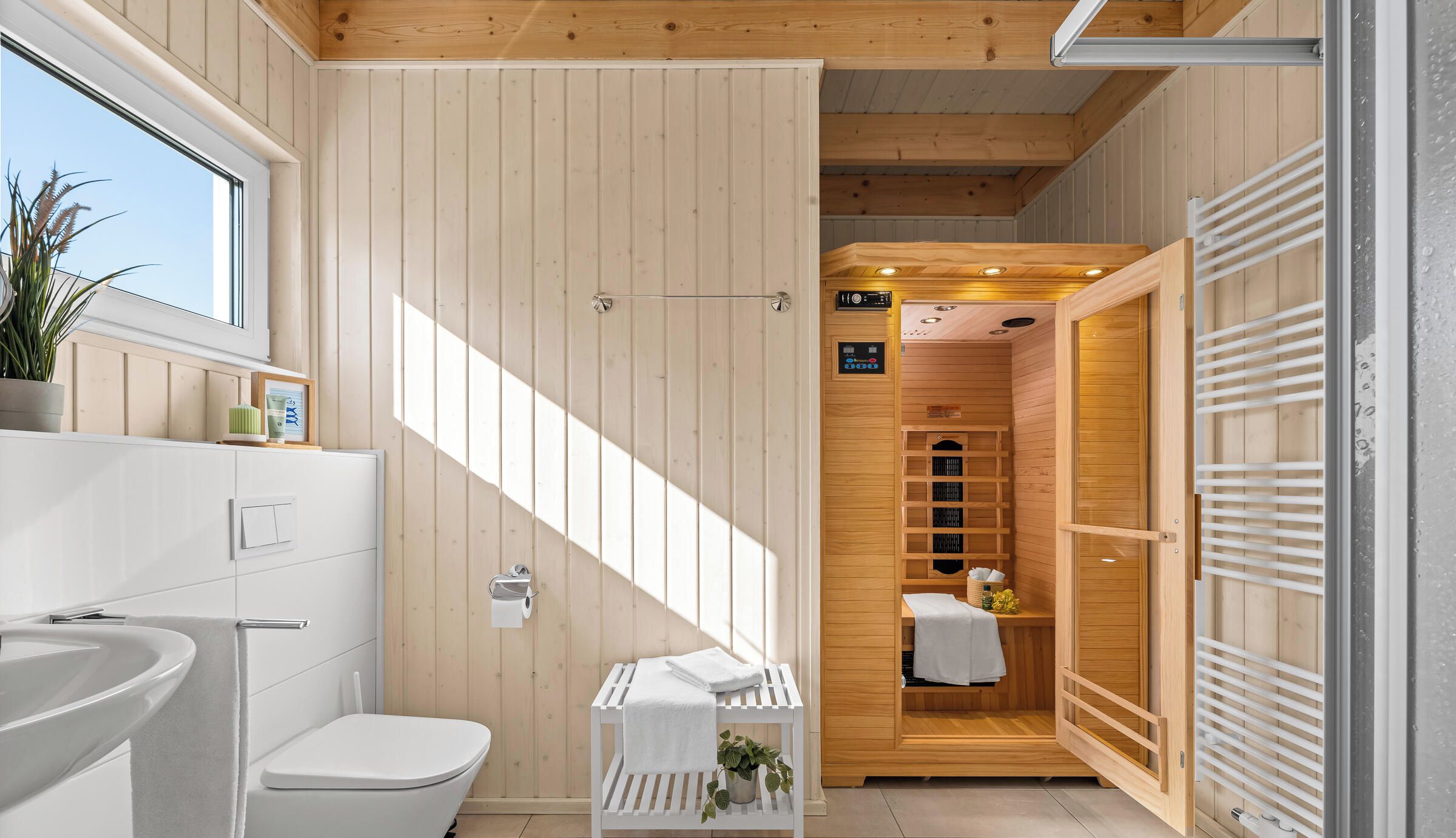Ein modernes Badezimmer mit Holzvertäfelung, einem weißen Waschbecken und einer Duschkabine.