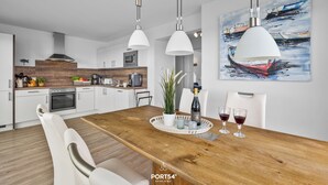 A modern kitchen with white cabinets, a wooden countertop, and pendant lighting. - Morgenlicht - Maisonette Apartment, Terrace, Infrared Sauna, Whirlpool, Sea View (Olpenitz)