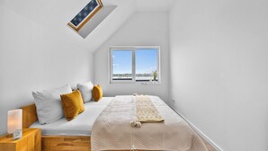 Un dormitorio con cama, mesita de noche, lámpara y ventana con vistas.