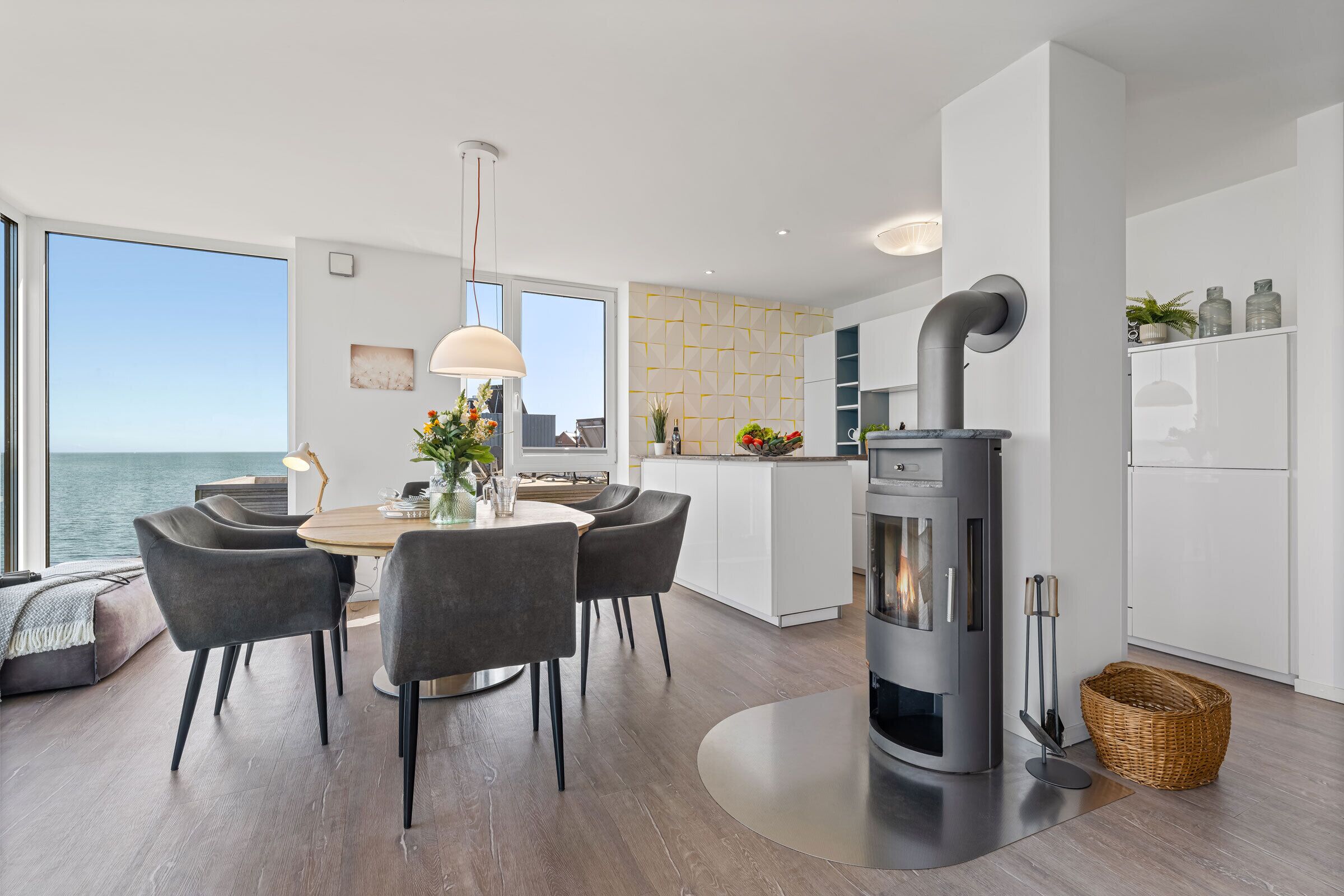 Une cuisine moderne dotée d’une cuisinière intégrée, d’un coin repas avec des chaises et offrant une vue sur la mer.