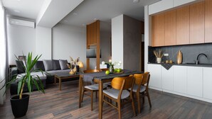 A modern living room with a sofa, dining table, chairs, and a potted plant.