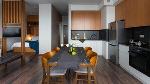 A modern kitchen with wooden cabinets, a black refrigerator, and a dining area with a table and chairs.