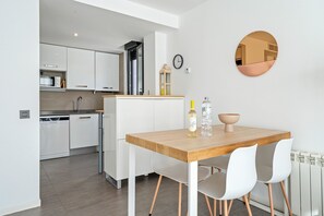A modern kitchen with white cabinets, a wooden countertop, and a dining area with a wooden table and white chairs.