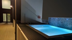 A modern indoor pool with a clear view of the pool area, a wooden floor, and a wall-mounted fire hydrant. - Appartamento di fronte al mare, piscina, aria condizionata, parcheggio ascensore (El Mas Mel)