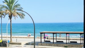 A beach view with a covered seating area, palm trees, and a clear sky. - Appartamento di fronte al mare, piscina, aria condizionata, parcheggio ascensore (El Mas Mel)