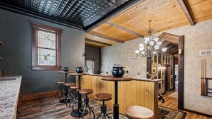 Eine Bar mit Holzhockern, einer Theke und einer Kristallleuchtre.