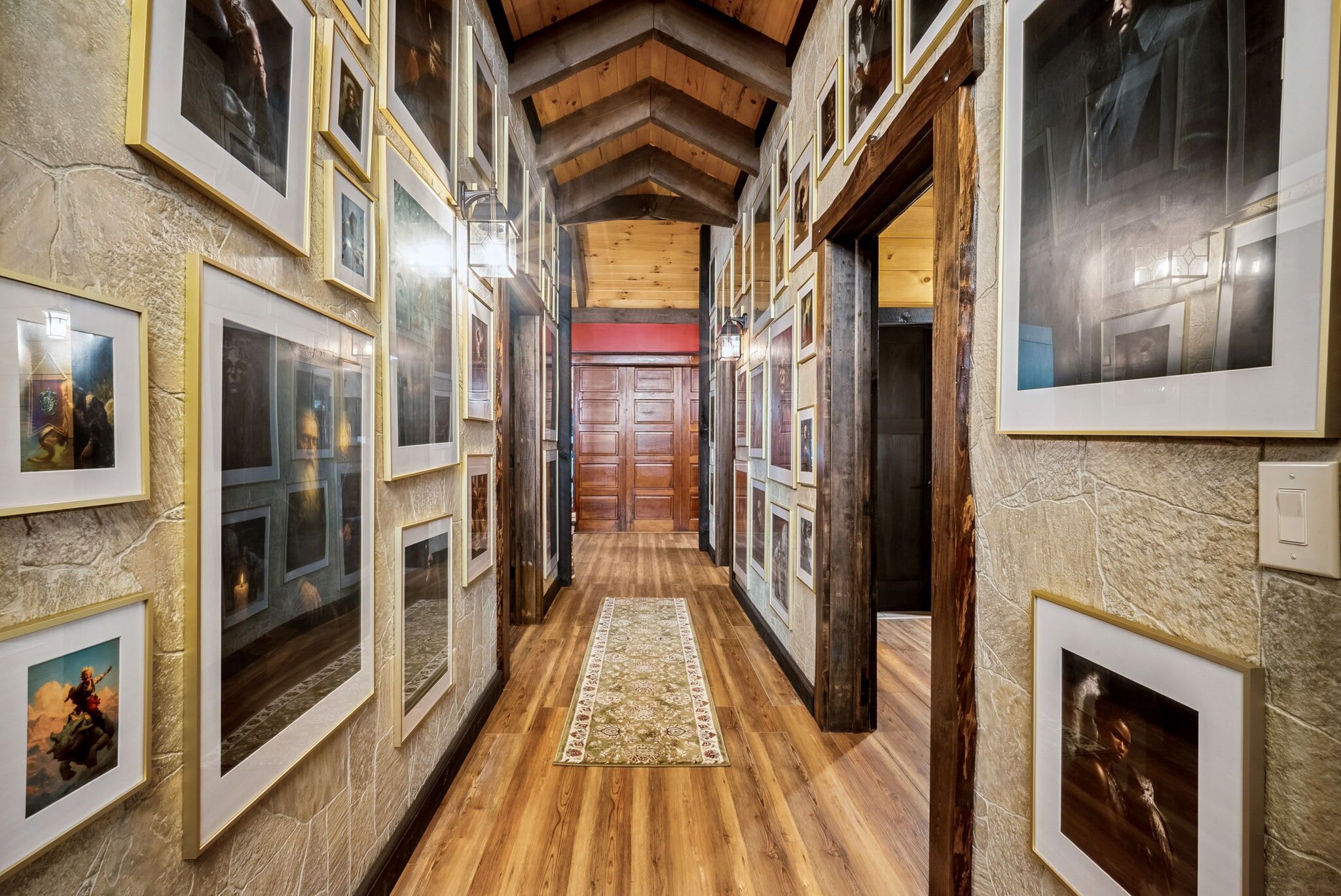 Un couloir avec des tableaux encadrés accrochés aux murs, un plancher en bois et un tapis à motifs.